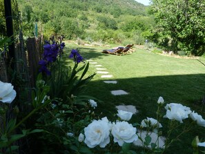 A garden with a lawn, flowers, and a wooden structure.