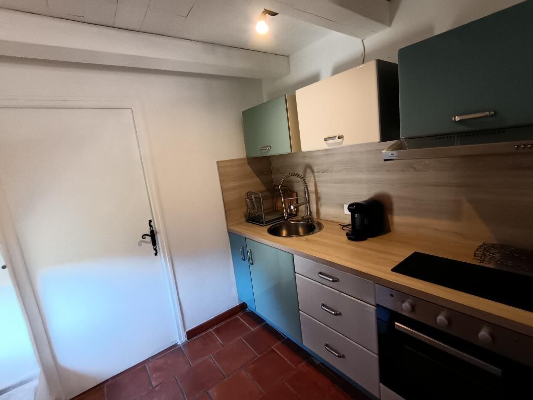 A compact kitchen with a white door, teal cabinets, a wooden countertop, and a built-in oven.