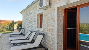 A stone building with a pool, outdoor lounge chairs, and a fan mounted on the wall. - Amazing home in Lisane Tinjske (Lisane Tinjske)
