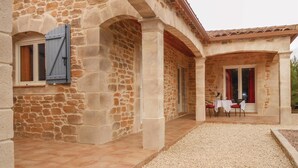 Un bâtiment en pierre doté d’une cour intérieure, comprenant une table et des chaises, ainsi qu’une fenêtre avec des volets.