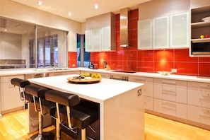 A modern kitchen with a central island, bar stools, and a large window.
