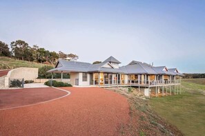 A modern house with a large driveway, a covered outdoor area, and a view of the surrounding landscape.