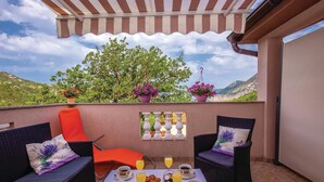 A balcony with wicker furniture, a table with drinks and snacks, and potted plants. - Cozy apartment in Bakarac with house sea view (Bakarac)