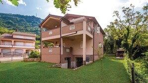 A multi-story building with balconies, a grassy yard, and a mountainous backdrop. - Cozy apartment in Bakarac with house sea view (Bakarac)