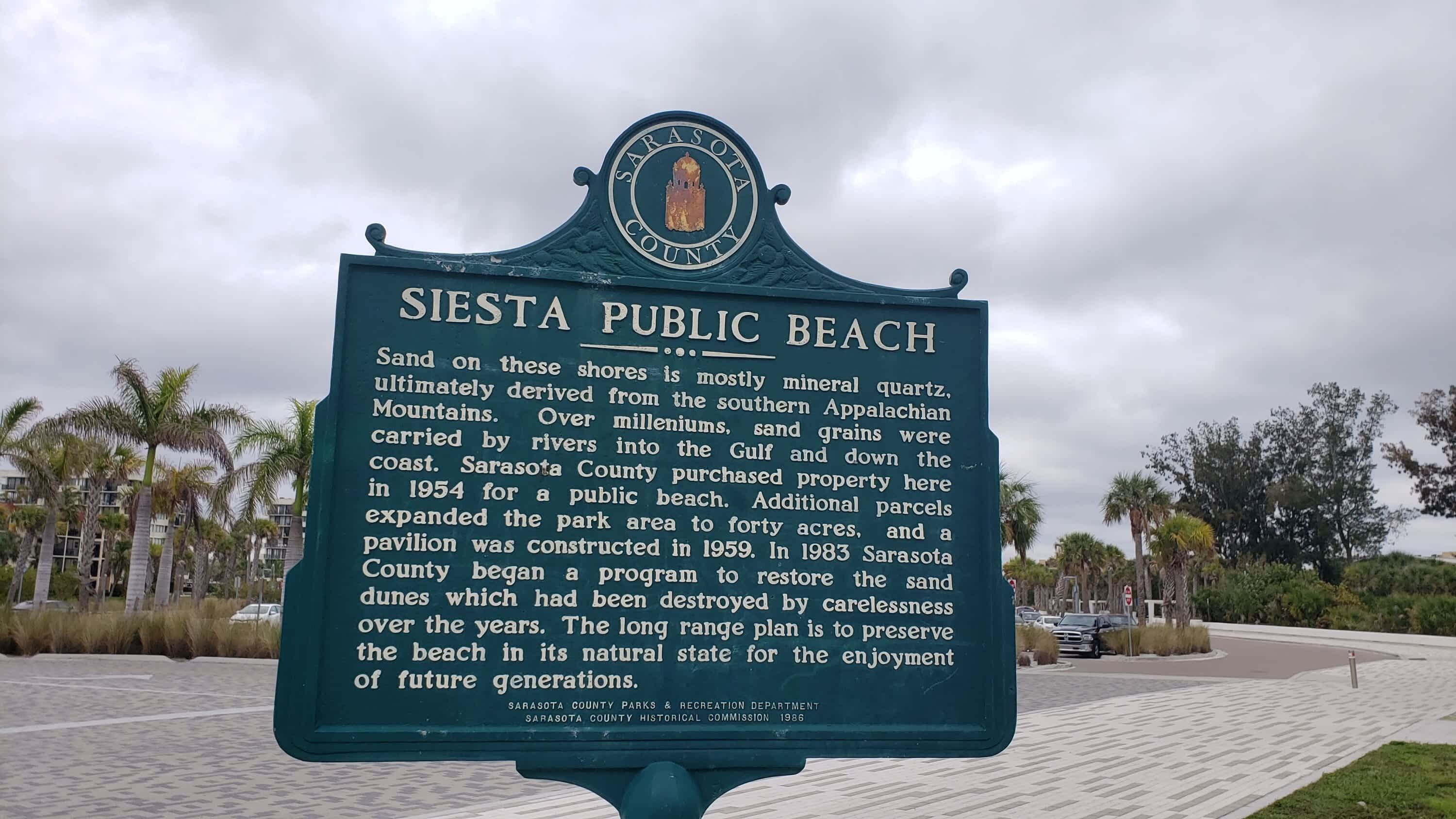A historical marker sign at Siesta Public Beach with information about the beach's geological history and conservation efforts.