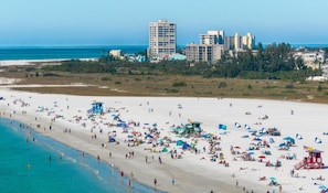 A beach with people, umbrellas, and lifeguard towers.