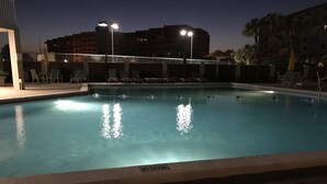 En pool på natten med solstolar och en skylt med texten ”Hoppa inte”.