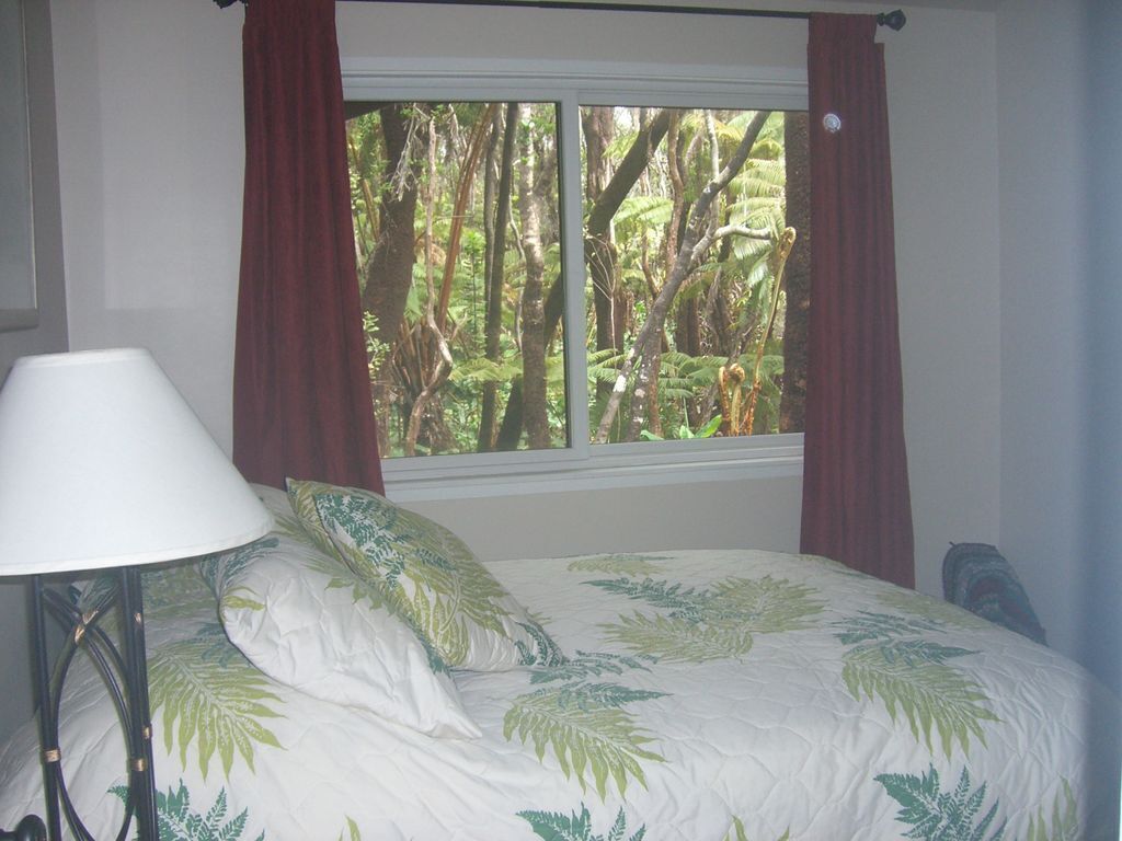 A bedroom with a bed, a lamp, and a window with curtains.