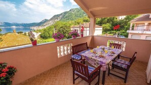 Un balcón con una mesa lista para dos personas, con vista a un paisaje de un lago y colinas.