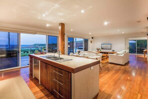 A modern kitchen with a large island, a dining area, and a living space with a view.