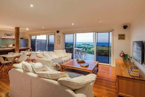 Un amplio espacio de estar con un sofá grande, una mesa de comedor y un televisor.