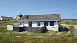 A coastal house with a white exterior, a dark roof, and a small porch. - 3 bedroom amazing home in Frøstrup (Frøstrup)