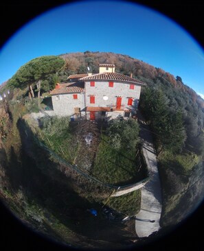 Situated on a hillside, this traditional building offers a tranquil setting with a paved path leading to its entrance.