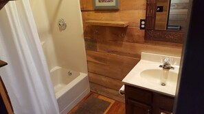 Une salle de bain avec une baignoire, un lavabo et un lambris en bois.