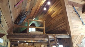 A rustic wooden interior with a loft area, wooden beams, and a ladder. - Seven Springs Cabin - Bear Claw Chalet - Authentic, Pet Friendly Log Cabin (Champion)