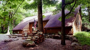 A rustic cabin with a wooden exterior, a sloped roof, and an American flag. - Seven Springs Cabin - Bear Claw Chalet - Authentic, Pet Friendly Log Cabin (Champion)