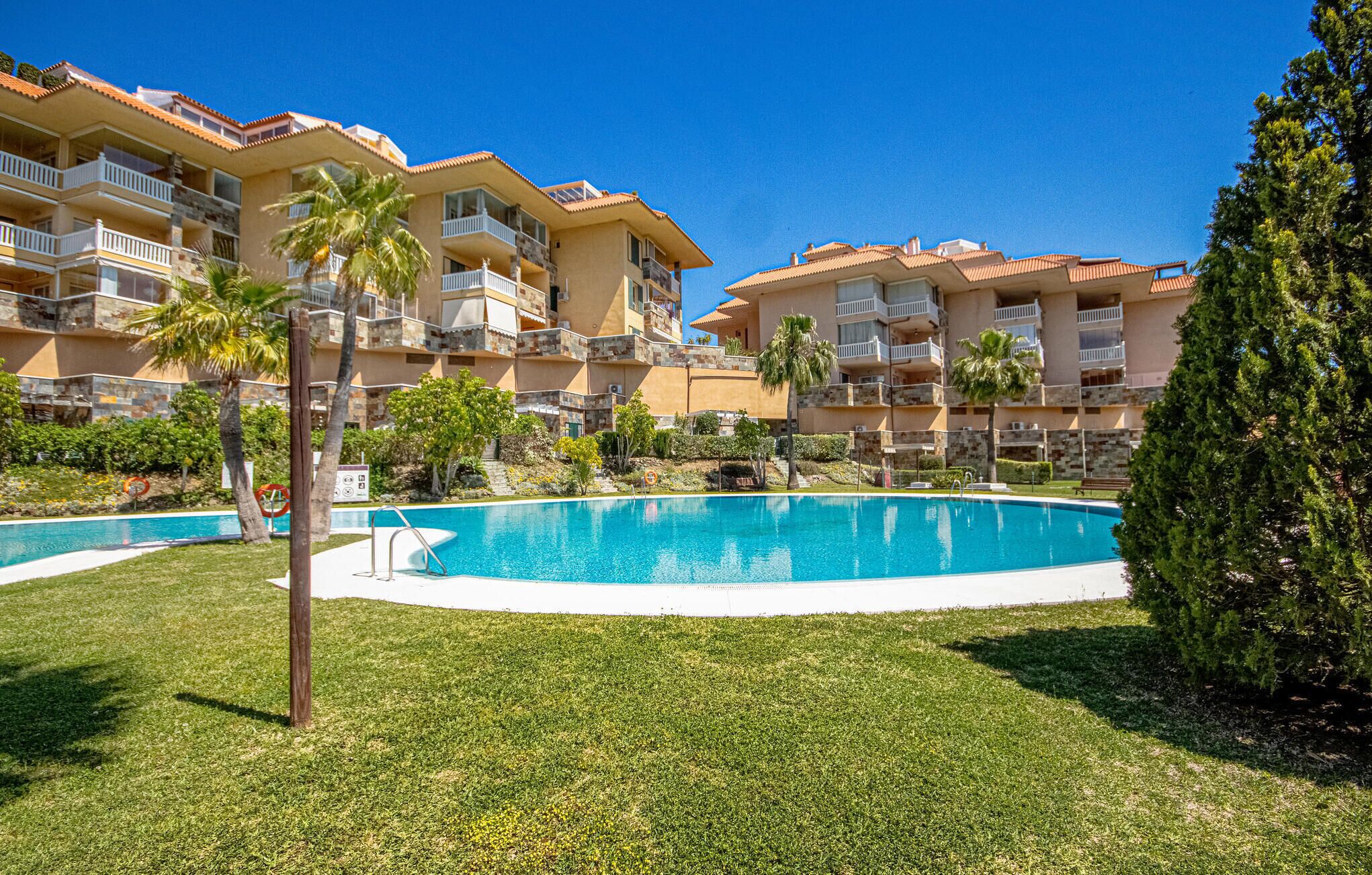 A resort with a large swimming pool, multiple-story buildings with balconies, and well-maintained landscaping.
