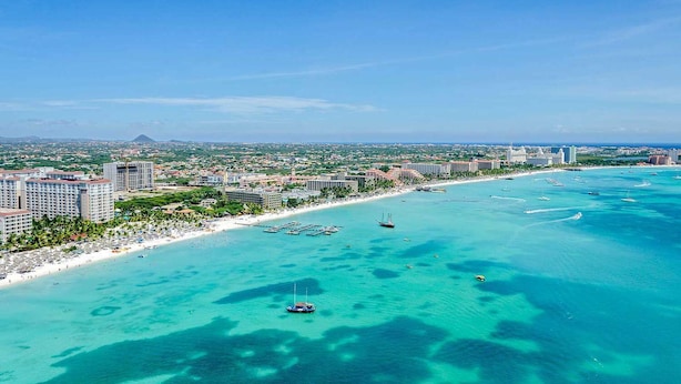 Eine Küstenstadt mit Strand, klarem türkisblauem Wasser und mehreren Hochhäusern.