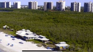 A beachfront property with multiple buildings, a sandy beach, and dense greenery. - Whole Home Villa in Hyde Park at Pelican Bay community with private pool/beach! (Naples)
