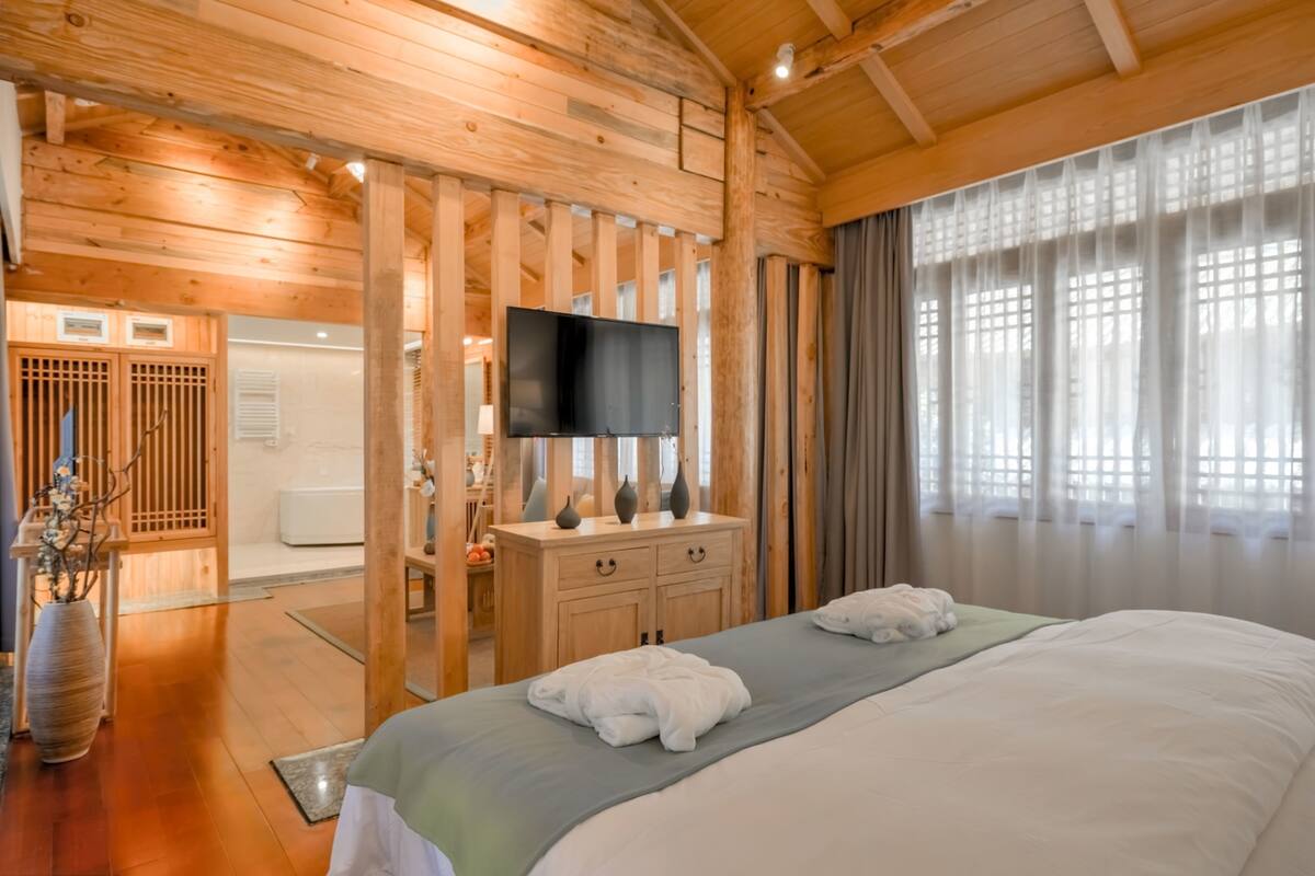 A wooden room with a bed, a TV, and a wooden cabinet.