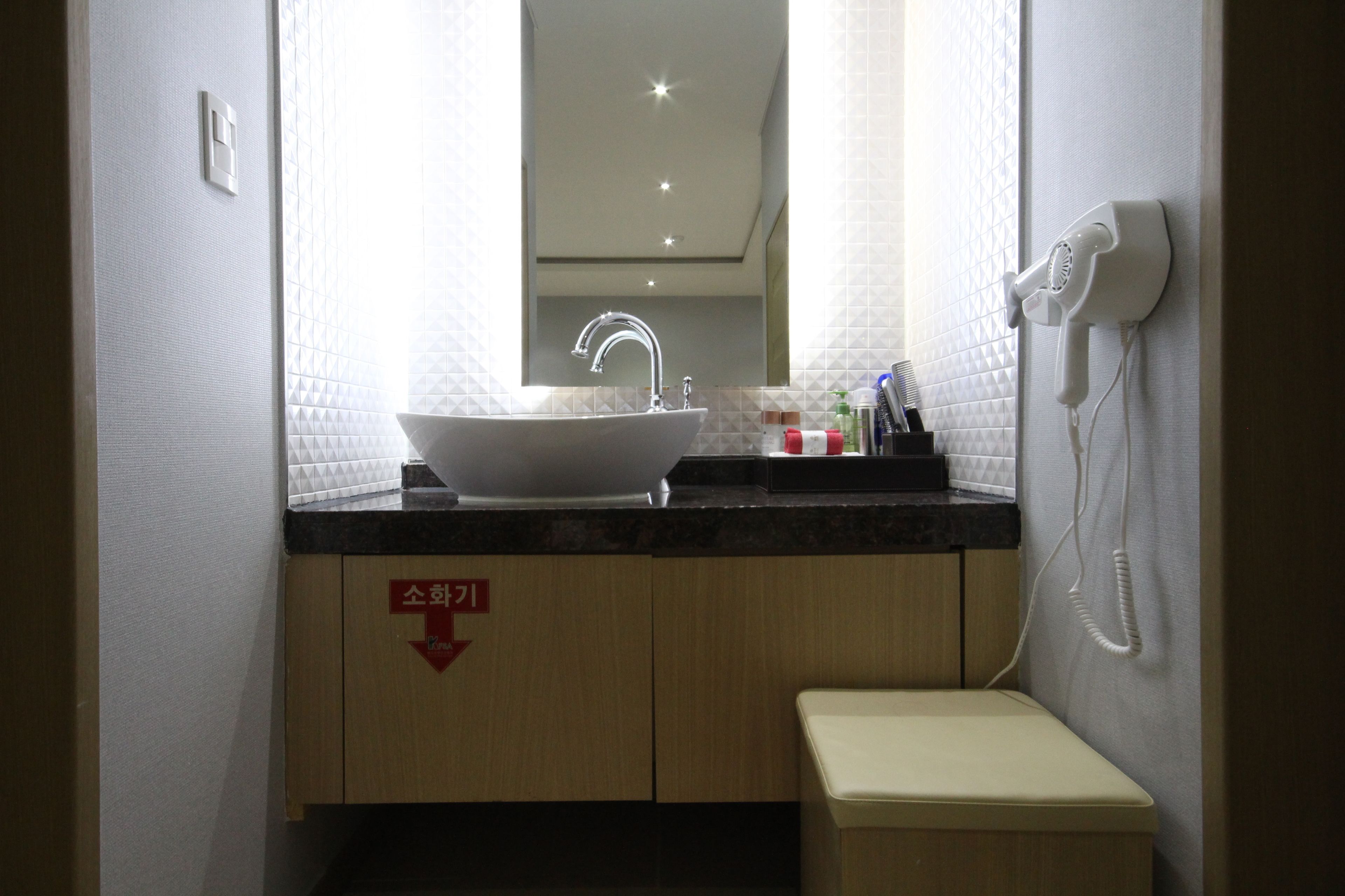 A bathroom with a sink, mirror, and a hairdryer on the wall.
