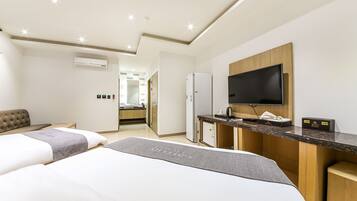 A hotel room with two beds, a kitchenette, a TV, and a minibar.