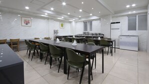 A conference room with a long table, multiple chairs, a refrigerator, and a window. - Gallery Hotel (Gwangju)