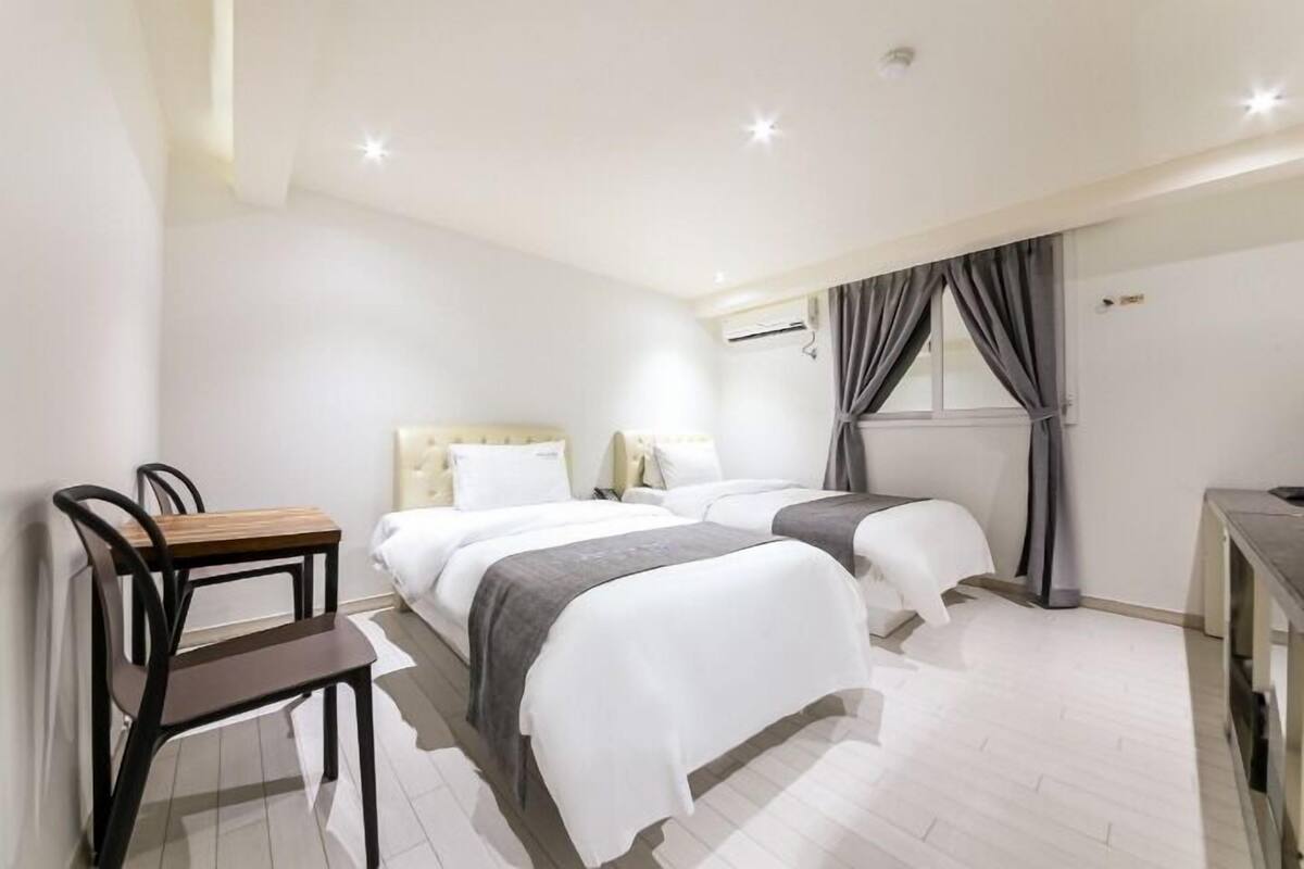 Una habitación de hotel con dos camas, un escritorio y una silla.