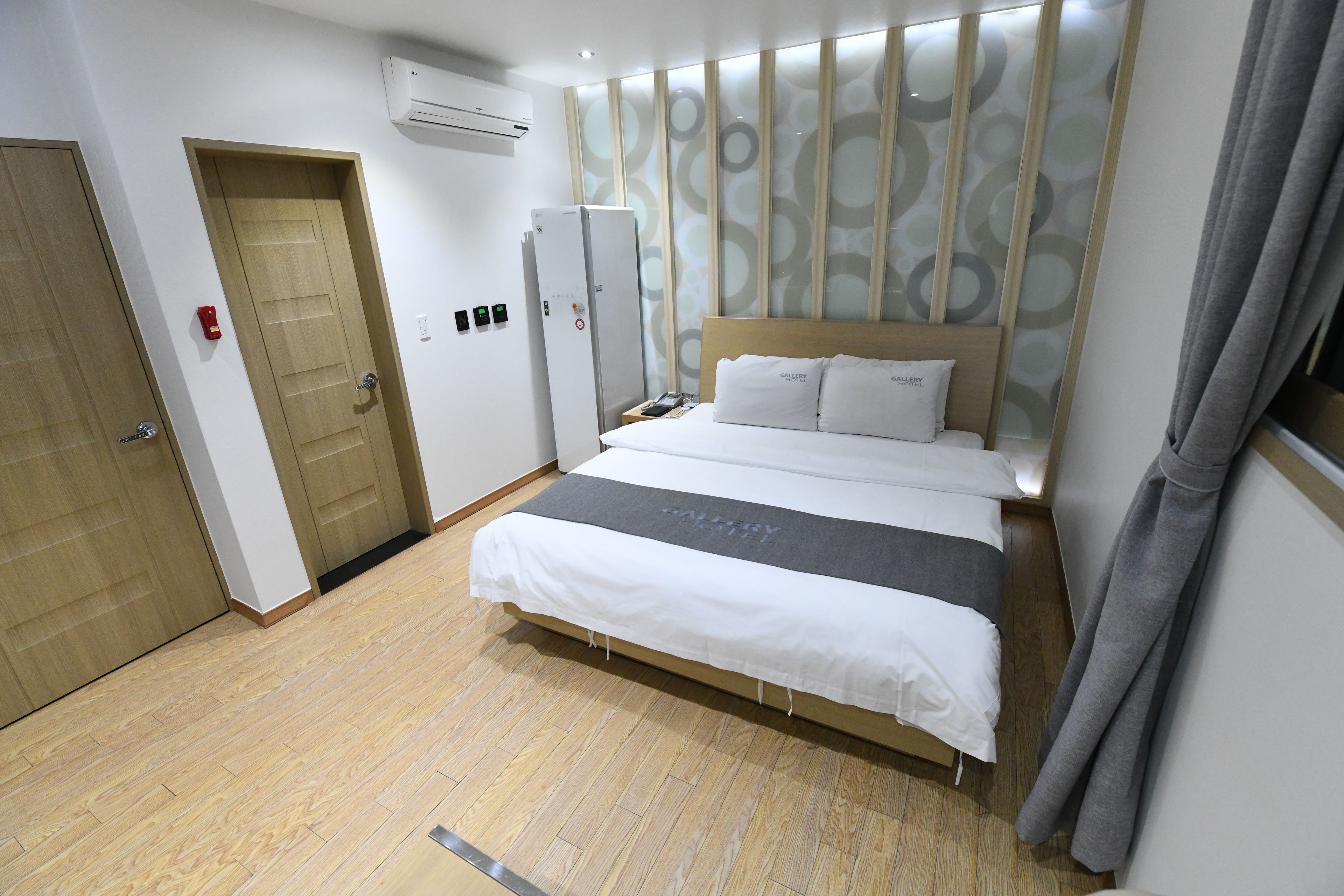 Una habitación de hotel con cama, armario, espejo y puerta.
