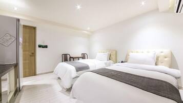 A hotel room with two beds, a desk, and a chair. There is a door and an air conditioning unit on the wall.