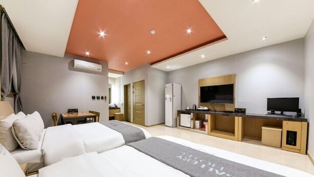 A modern hotel room with a large bed, a desk, a TV, and an air conditioning unit. - Gallery Hotel (Gwangju)