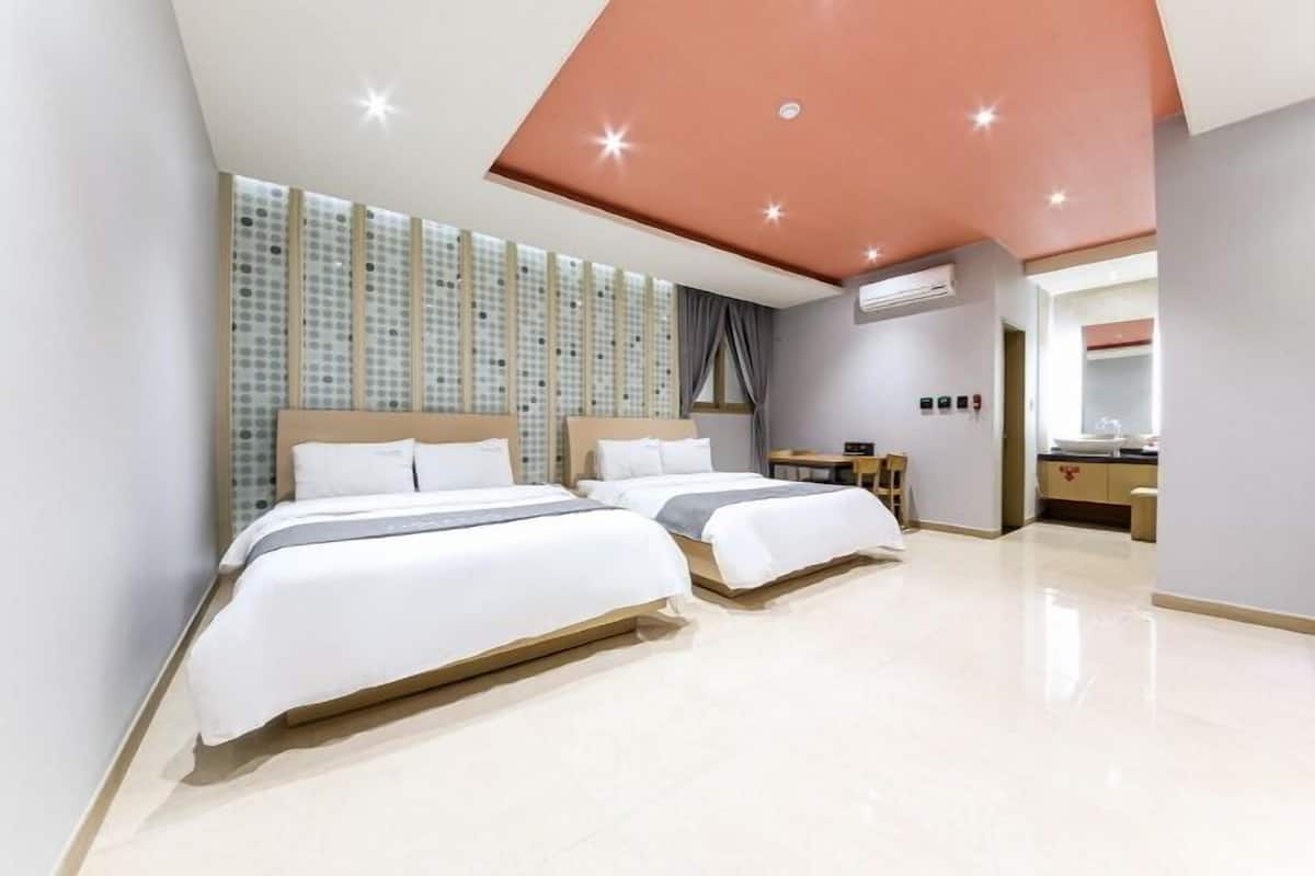 Una habitación de hotel moderna con dos camas, un escritorio y un tocador.
