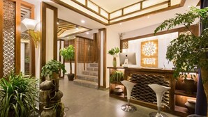 A reception area with a wooden reception desk, potted plants, and a staircase leading to another floor. - Floral Hotel Lijiang Exclusive Memory (Lijiang)