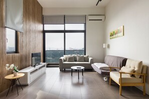 A modern living room with a sofa, a coffee table, and a TV on a wooden cabinet. - The Establishment at Bangsar KL Sentral (Kuala Lumpur)