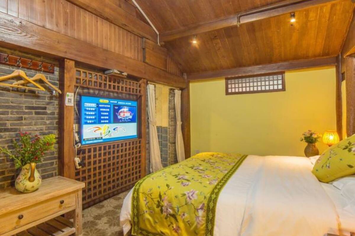 Une pièce en bois avec un lit, une télévision et une petite table sur laquelle se trouve un vase.