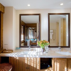 Une salle de bain avec deux lavabos, un miroir et un meuble en bois.