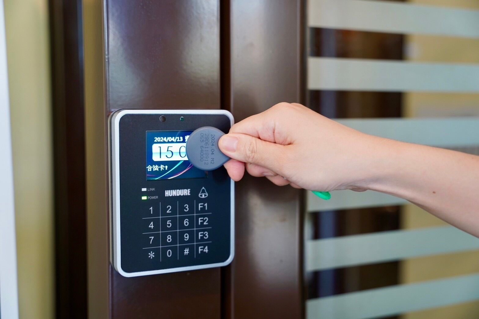 A hand inserting a key into a digital keypad lock on a door.