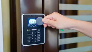 A hand inserting a key into a digital keypad lock on a door.