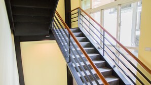 A staircase with a black handrail and wooden steps, leading to a landing with a window.