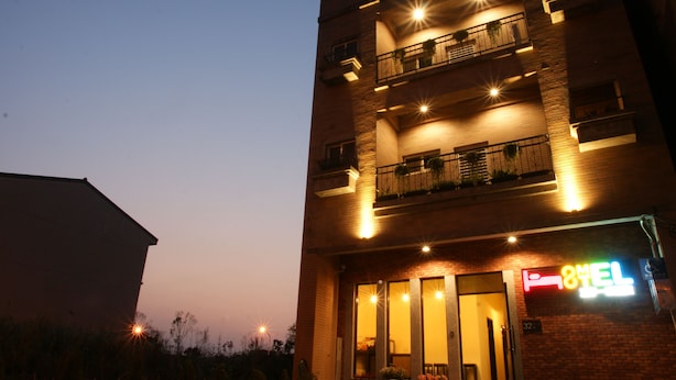 A multi-story hotel with balconies, a neon sign, and a brick facade.