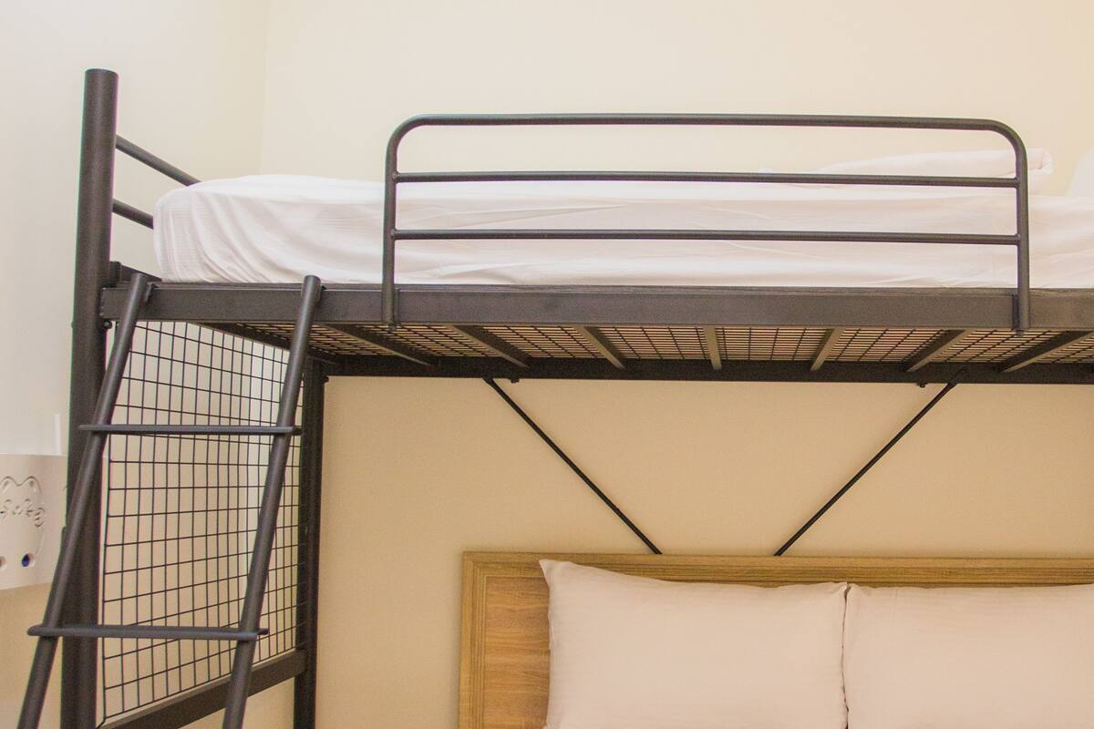 Ein Stockbett mit einer Leiter, weißer Bettwäsche und einem Holzkopfteil.