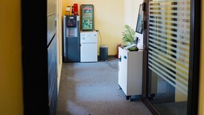 A hallway with a coffee machine, a clock, and a vending machine.