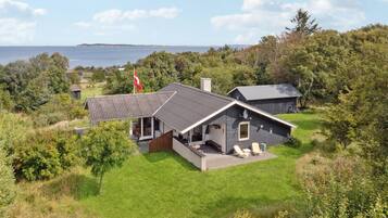 A modern house with a large deck, a garage, and a view of the sea.