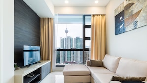 Una sala de estar moderna con un televisor de pantalla plana, un sofá color beige y un ventanal con vistas a la ciudad.
