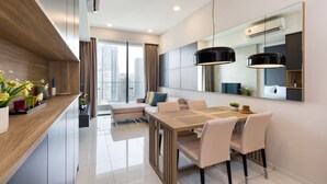 Un comedor moderno con una mesa de madera, sillas blancas y un espejo grande en la parte superior.