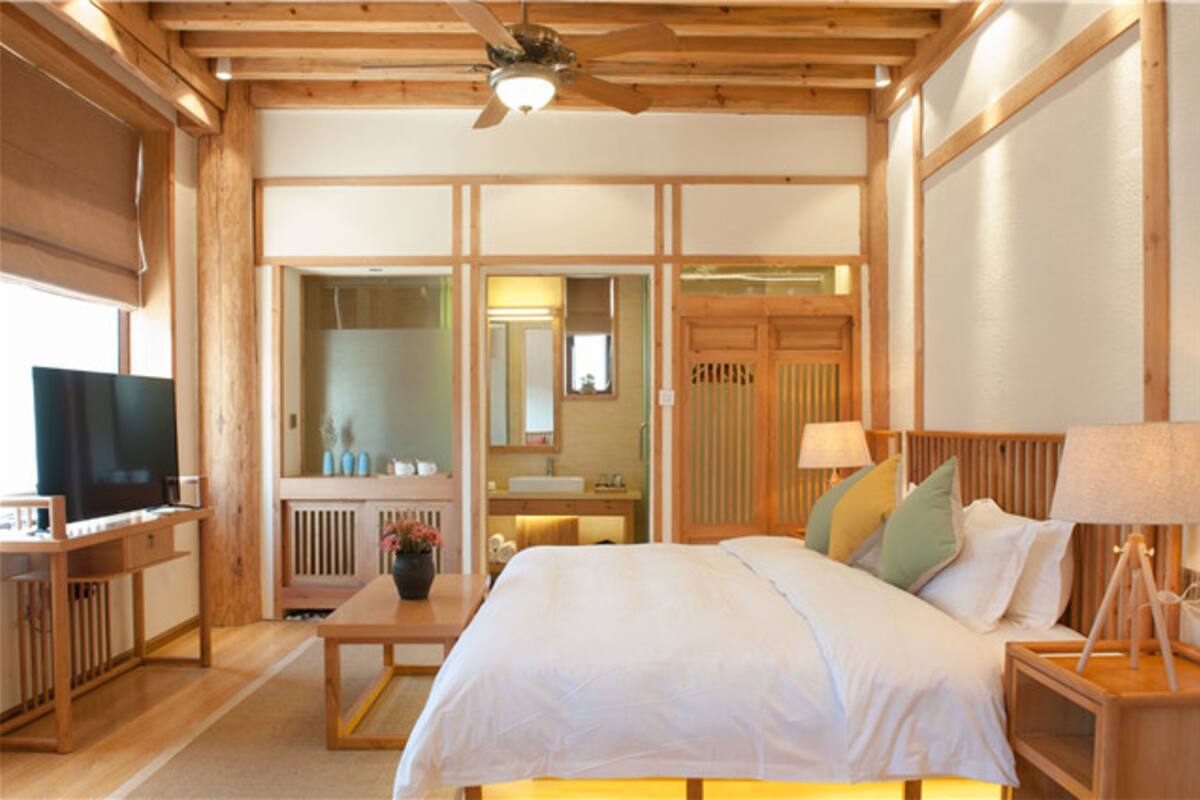 Una habitación de madera con cama, televisor, escritorio y ventilador de techo.