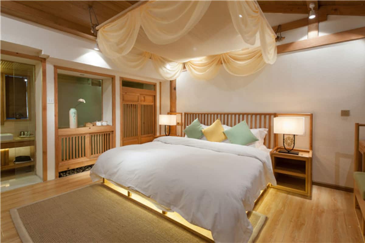Un dormitorio con una cama grande, cabecera de madera, lámparas de noche y dosel.