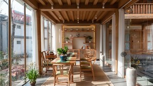 Un comedor amplio con mobiliario de madera, una mesa central y plantas en macetas.