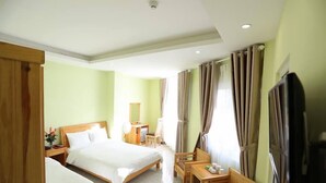 A hotel room with two single beds, a wooden desk, a chair, a TV, and a window with curtains. - Trung Nhan Hotel (Cam Ly - Da Lat)