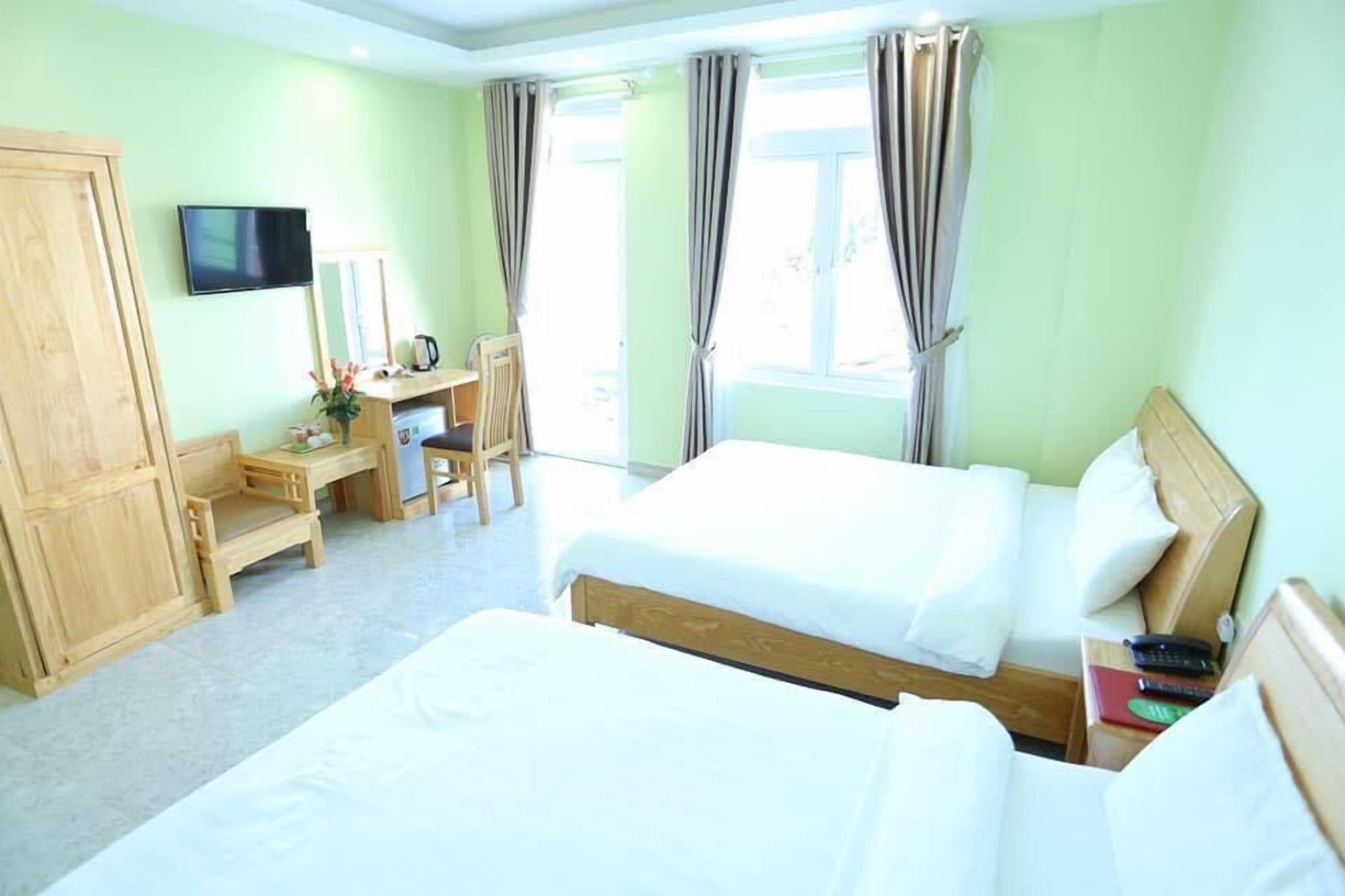 A hotel room with two beds, a desk, a chair, a TV, and a wardrobe.